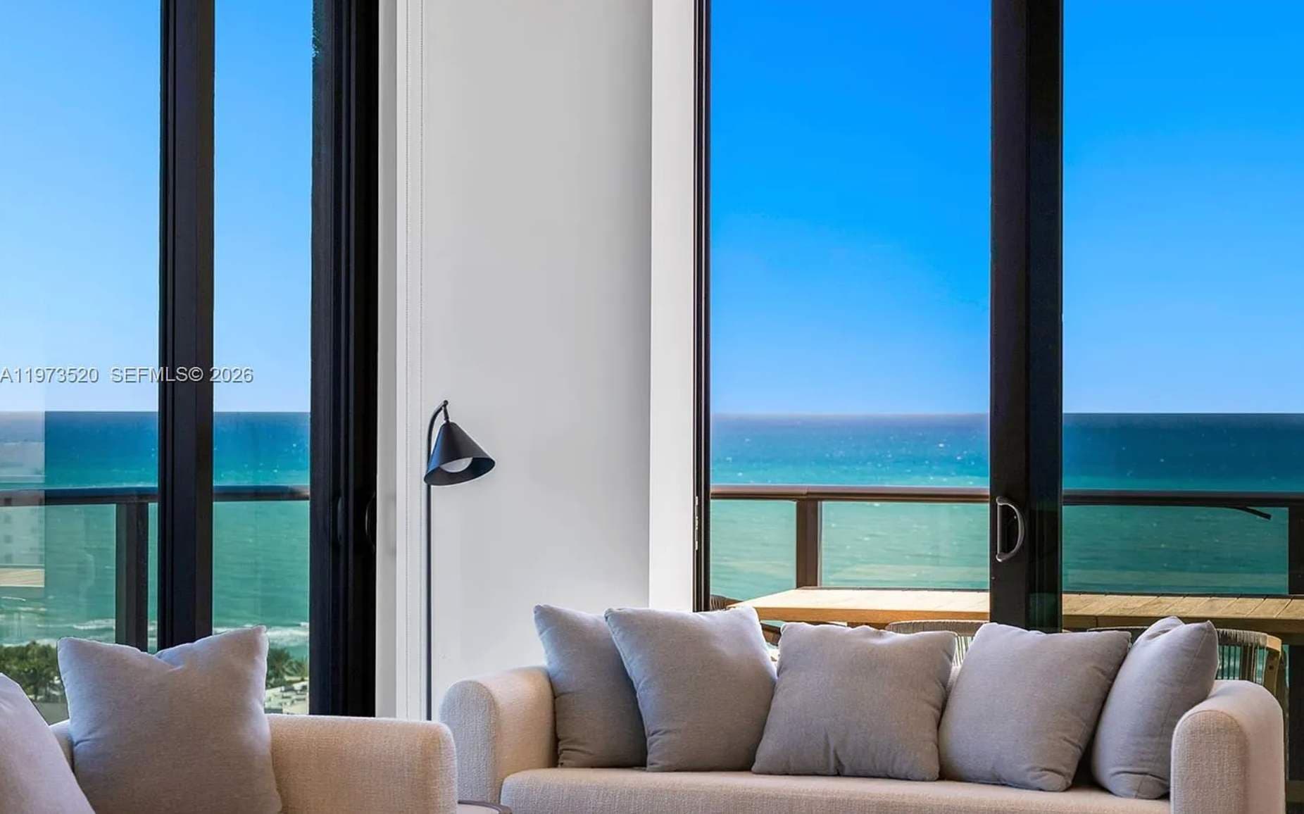 Massive floor-to-ceiling windows framing the coast.