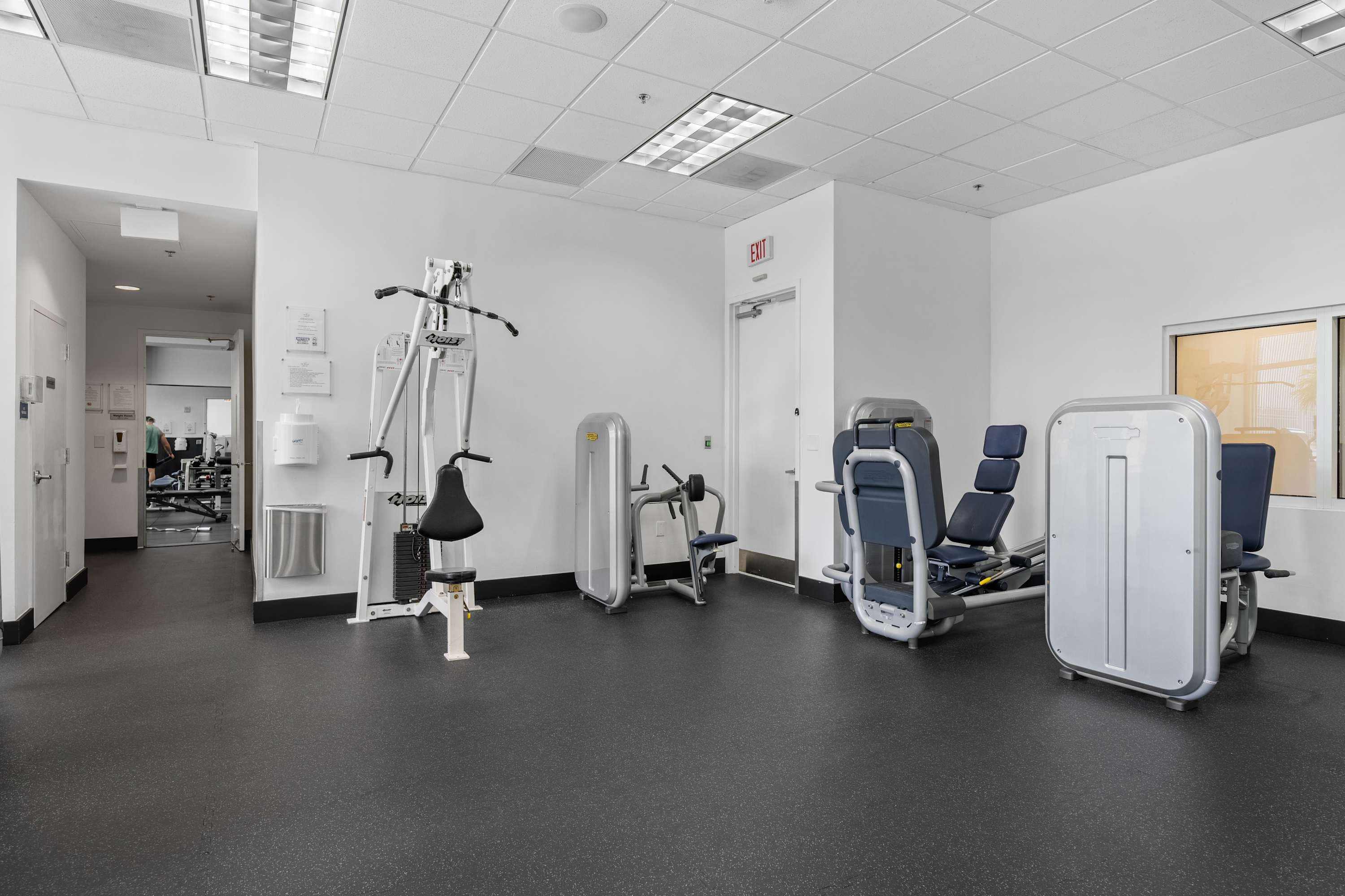 Gym with strength machines and dark flooring.
